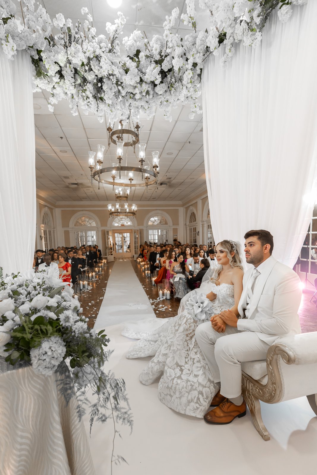 Pareja de novios sentada en ceremonia con altar de flores blancas y velas en Cartagena