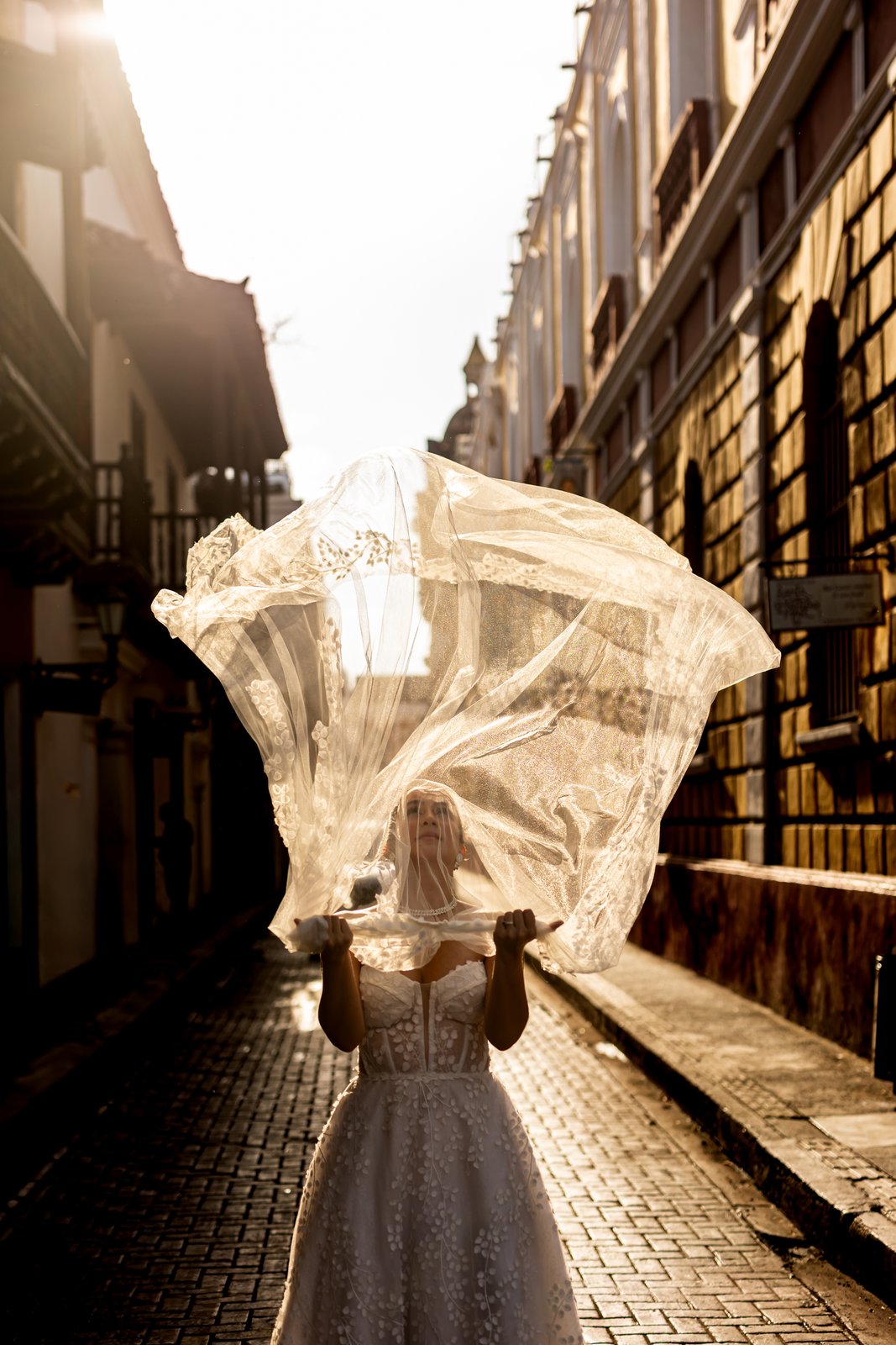 Novia con velo al viento en callejón de Cartagena al atardecer
